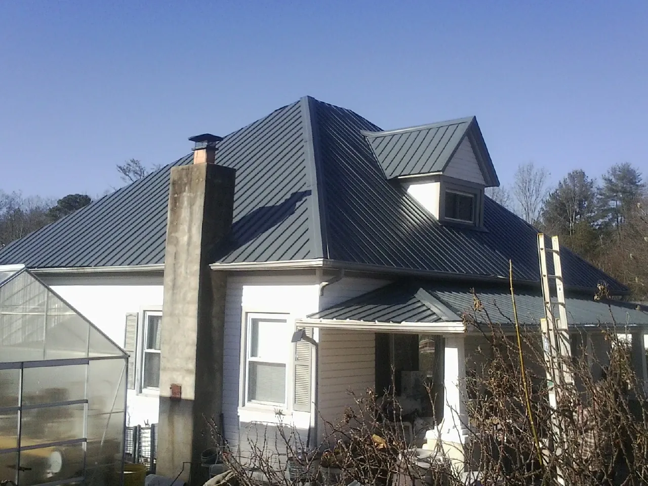 Dark blue standing seam metal roof on a white farmhouse with dormer — Slate & Tile Roof Repair by Roofing Brothers in Heath