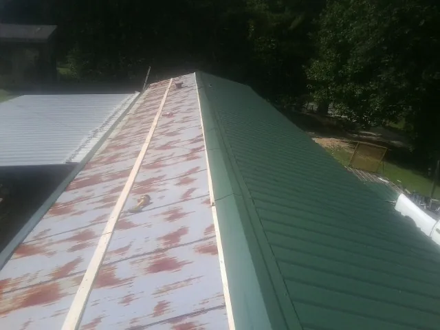 Old rusted panels beside newly installed green metal roofing — Wind Damage Roof Repair by Roofing Brothers in Heath