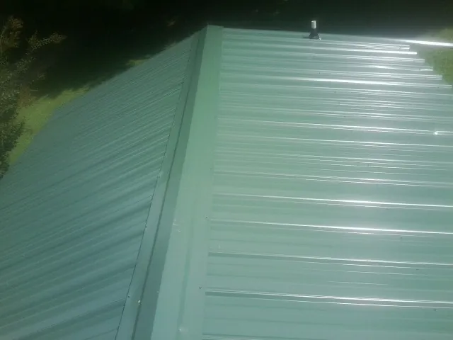 New green metal panels meeting at the ridge of a roof — Flat Roof Repair work by our crew in Heath