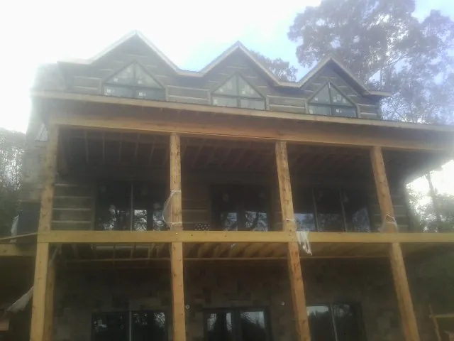 Dormers and porch framing on a large log home under construction — Roof Coating work by our crew in Heath
