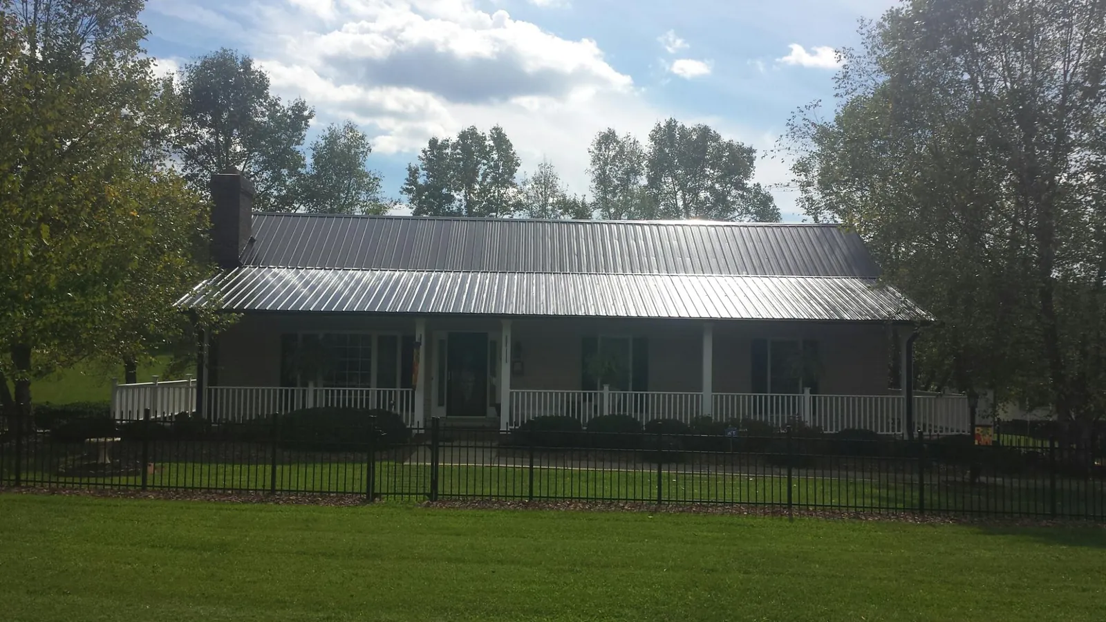 Gray metal roof on a brick ranch with a full width front porch — Gutter Guard Installation work by our crew in Heath