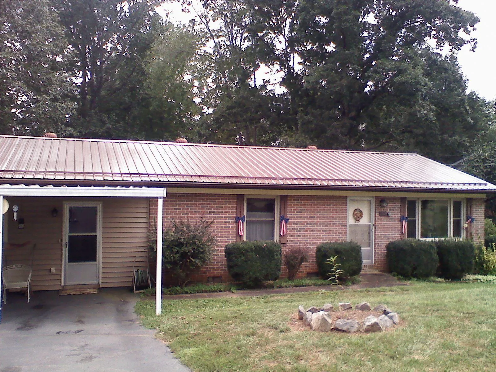 Bronze metal roof and carport on a brick ranch home — Roof Repair work by our crew in Heath