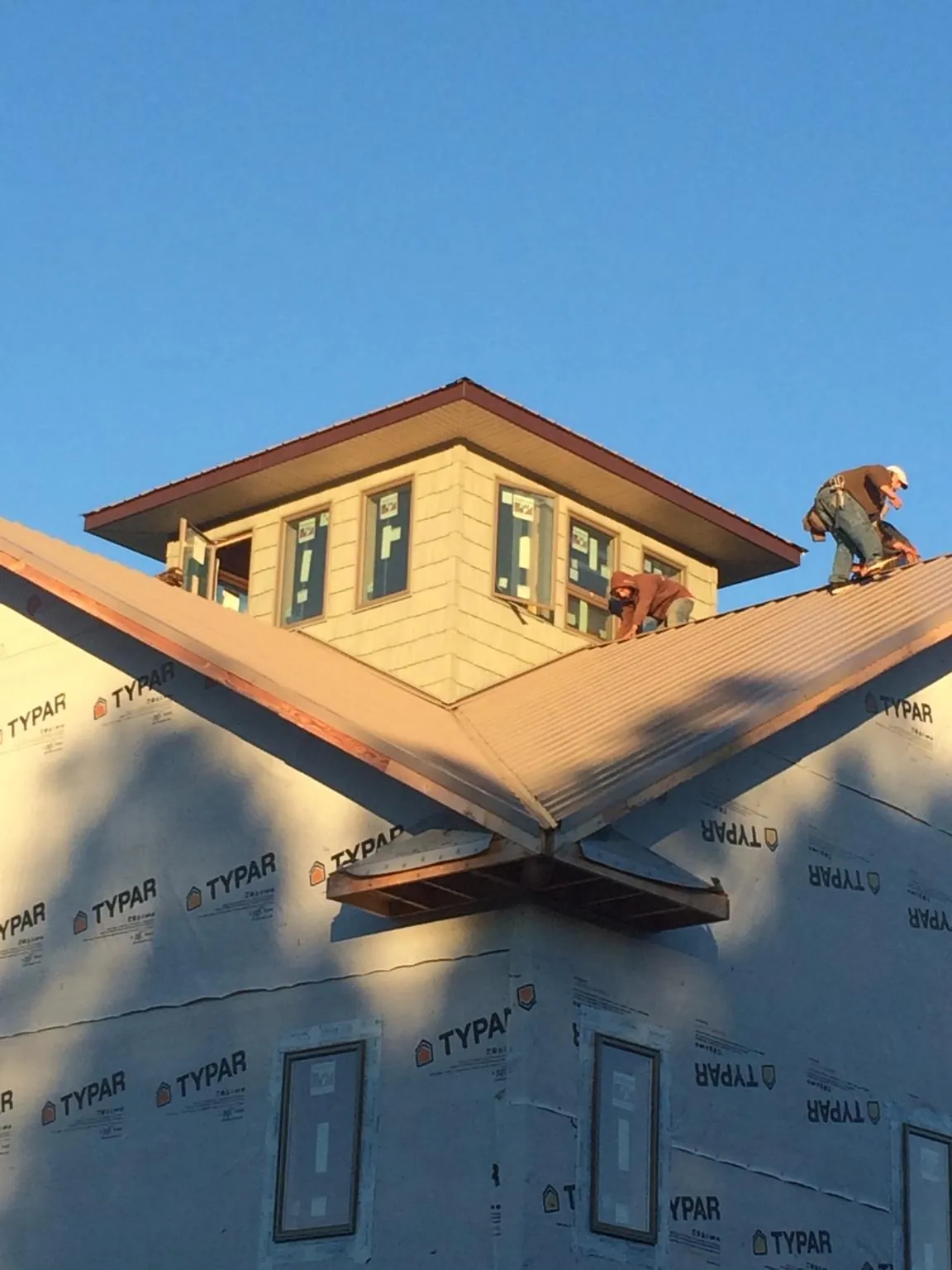Roofers working around a rooftop cupola on a new metal roof at sunset — Roof Waterproofing in Heath by Roofing Brothers